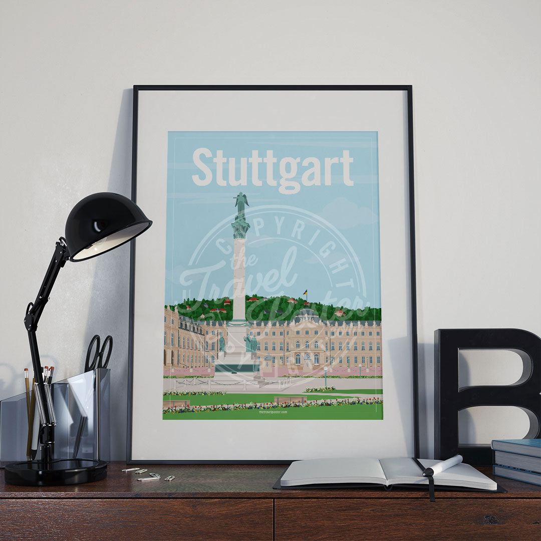 a frame with a poster of the Stuttgart Schlossplatz, placed a wooden sideboard with a table lamp and stationery supplies
