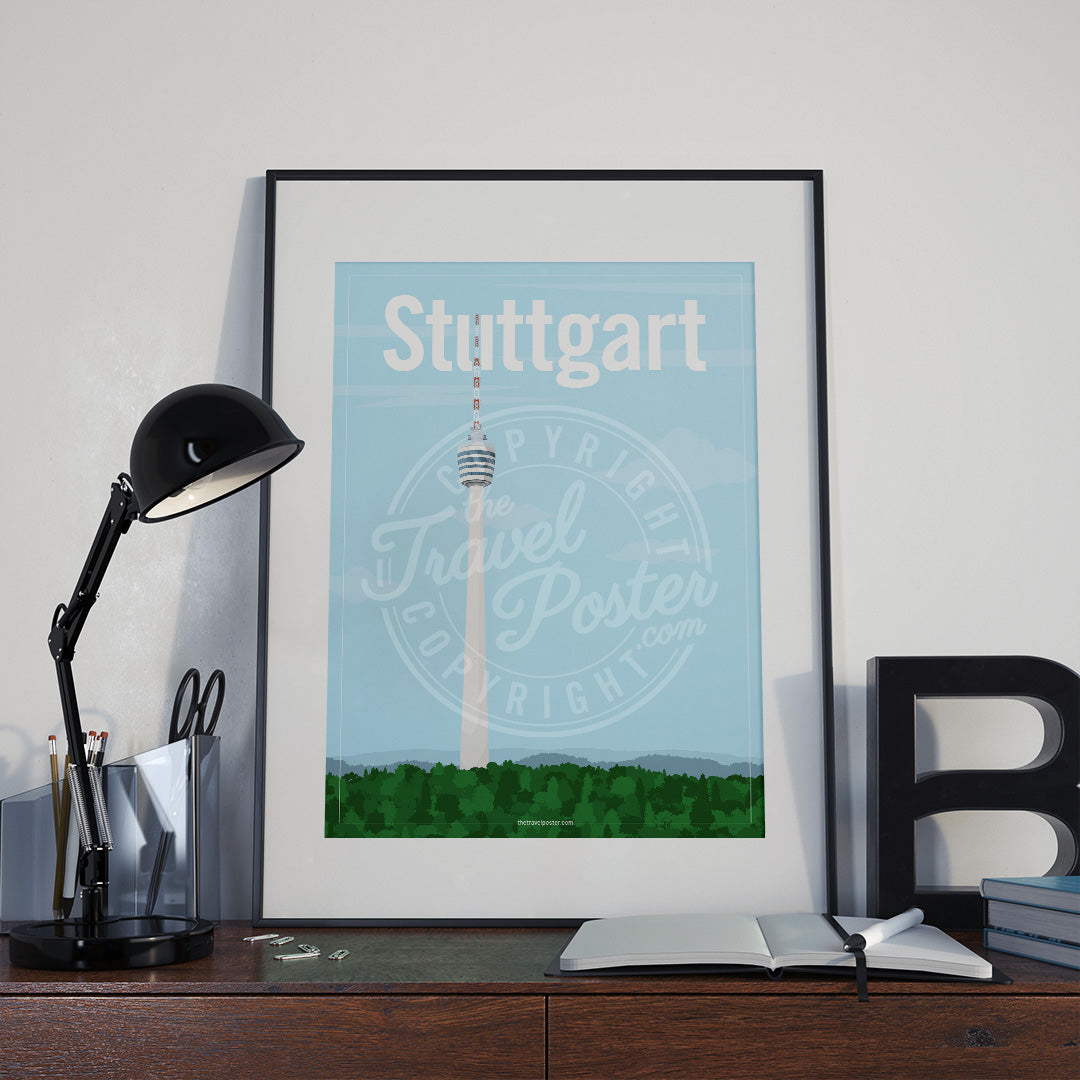 a frame with a poster of the Stuttgart TV Tower, placed a wooden sideboard with a table lamp and stationery supplies