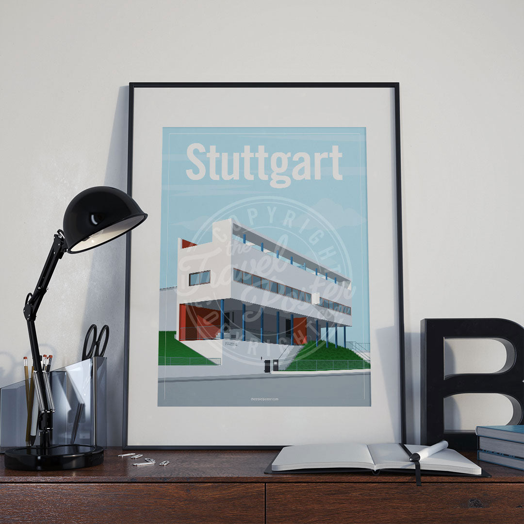 a frame with a poster of the Stuttgart Weissenhof Museum, placed a wooden sideboard with a table lamp and stationery supplies