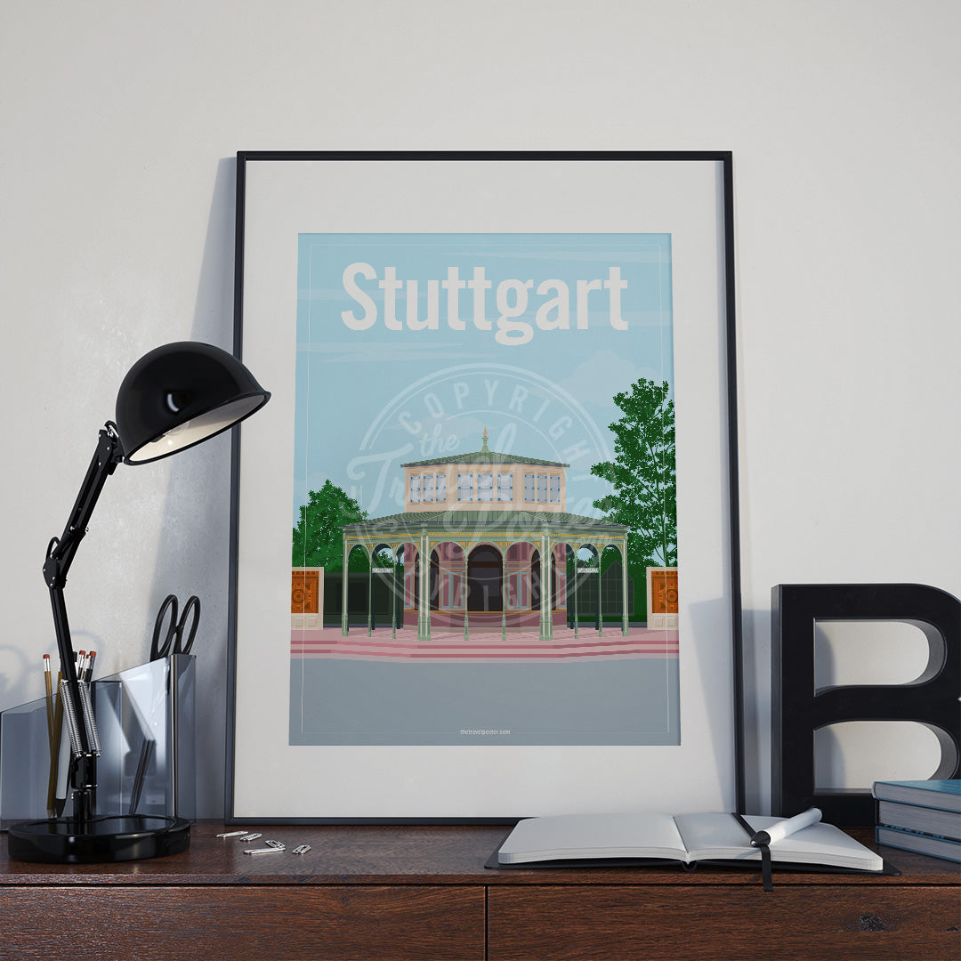 a frame with a poster of the Stuttgart Wilhelma Kassenpavillon, placed a wooden sideboard with a table lamp and stationery supplies