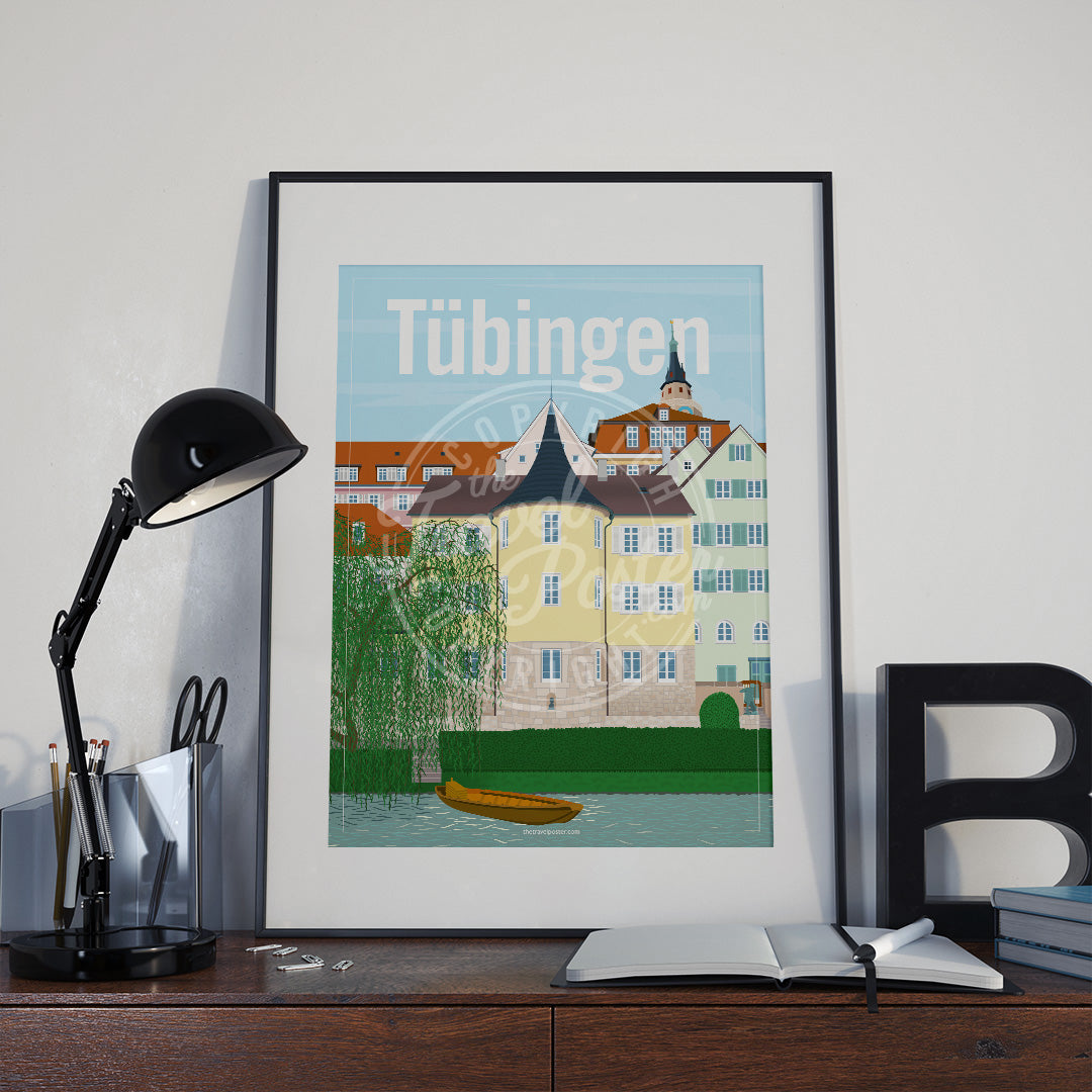 a frame with a poster of the Tübingen Holderlinturm, placed a wooden sideboard with a table lamp and stationery supplies