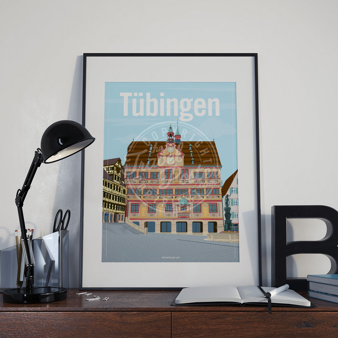 a frame with a poster of the Tübingen Rathaus, placed a wooden sideboard with a table lamp and stationery supplies