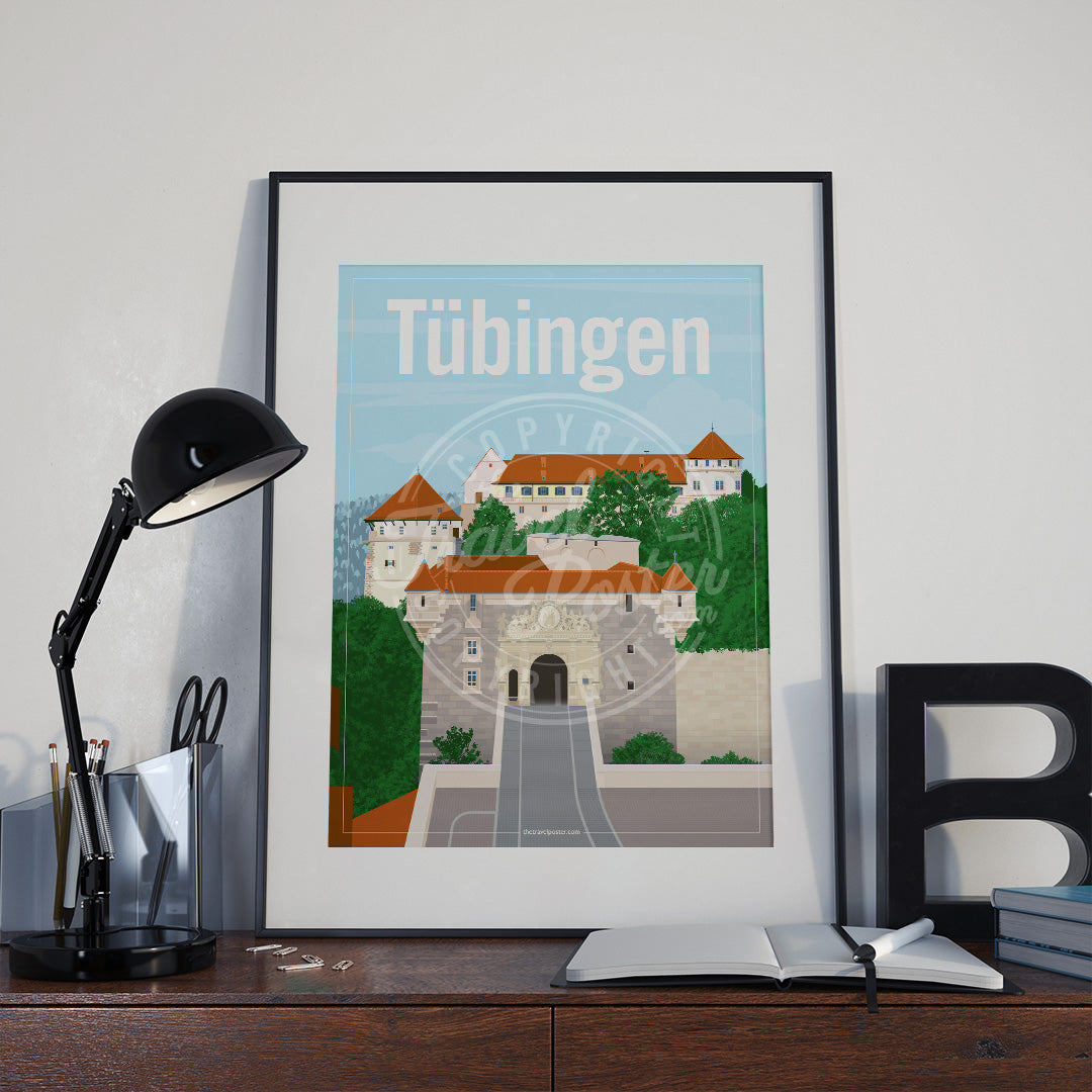 a frame with a poster of the Hohentübingen Castle, placed a wooden sideboard with a table lamp and stationery supplies