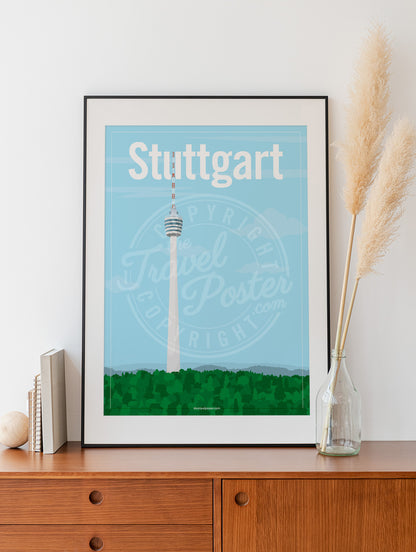 a frame with a poster of the Stuttgart TV Tower, placed on a wooden sideboard with some books and reeds in a glass bottle